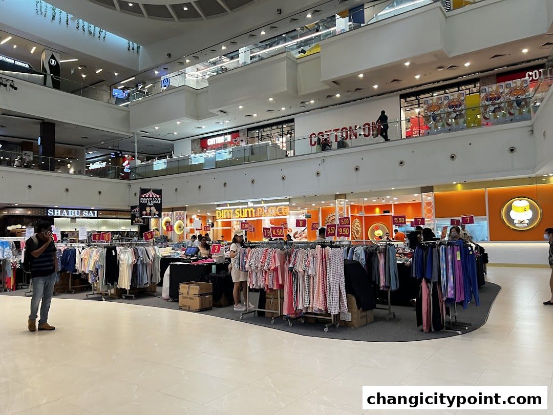 A retail store display with racks of clothing and price tags in a shopping mall.