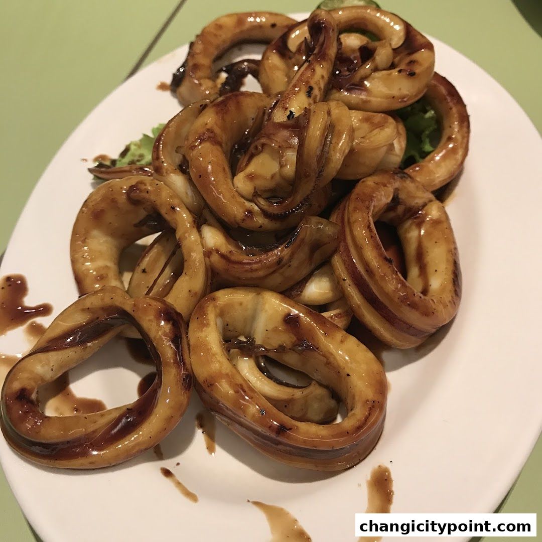 A plate of glistening, glazed calamari rings served with a light garnish.