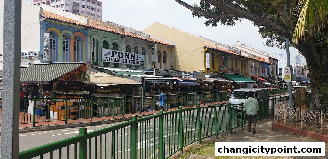 A row of colorful shops, with Ponni Indian Groceries prominently displayed.