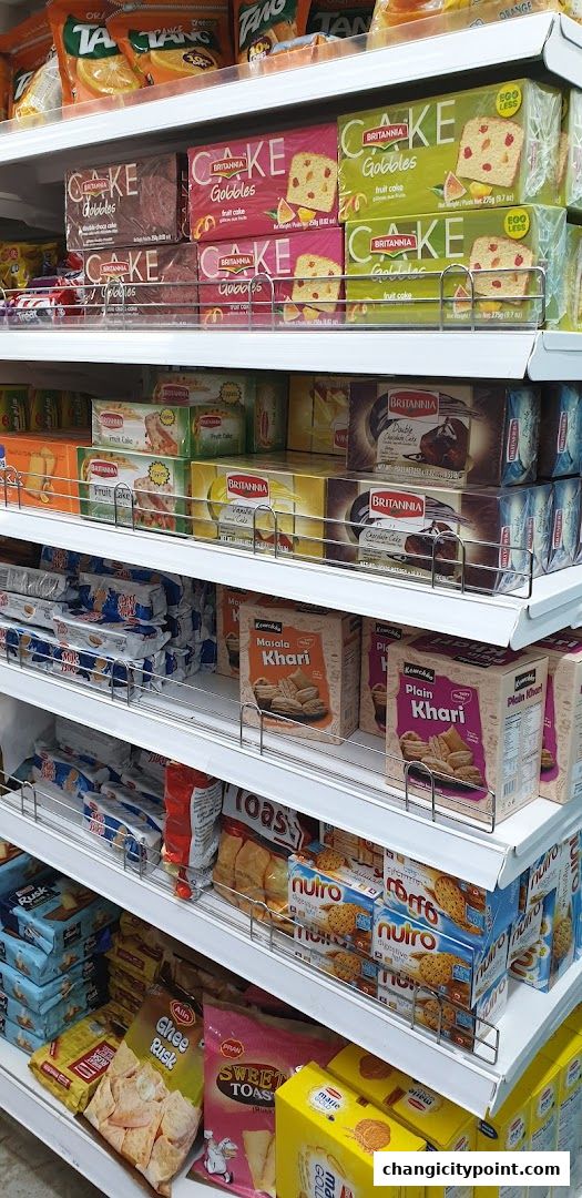 Shelves stocked with various Indian snacks, biscuits, and cakes from Ponni Indian Groceries.