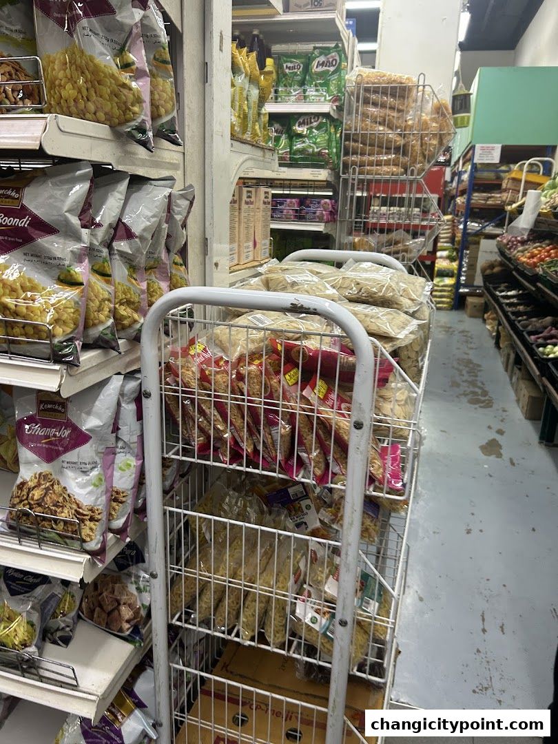 Aisle of an Indian grocery store with shelves stocked with various food items and snacks.