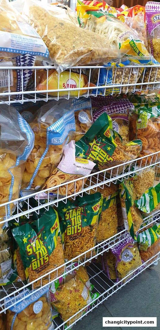 Shelves stocked with various packaged Indian snacks and savories.
