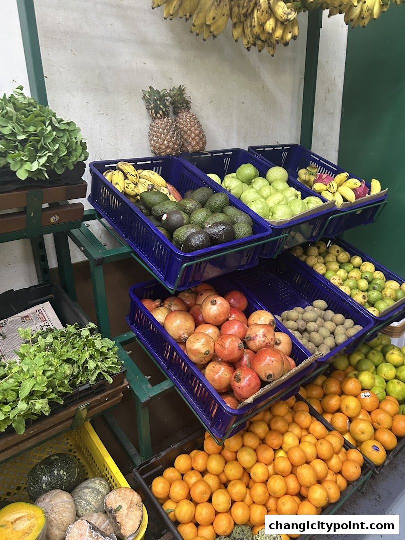 A vibrant display of fresh fruits and vegetables, including bananas, avocados, guavas, pomegranates, and oranges.