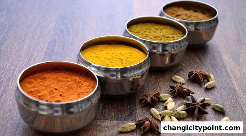 Bowls of colorful Indian spices and whole spices on a wooden surface.