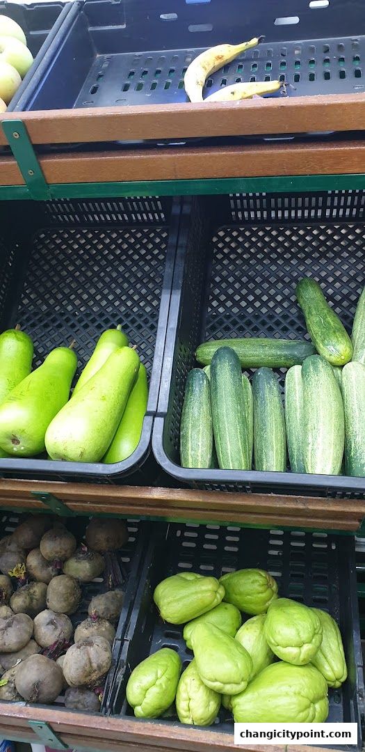 A display of fresh produce including gourds, cucumbers, beets, and chayote squash.