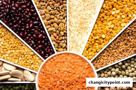 A vibrant collage of various Indian lentils, beans, and rice varieties.