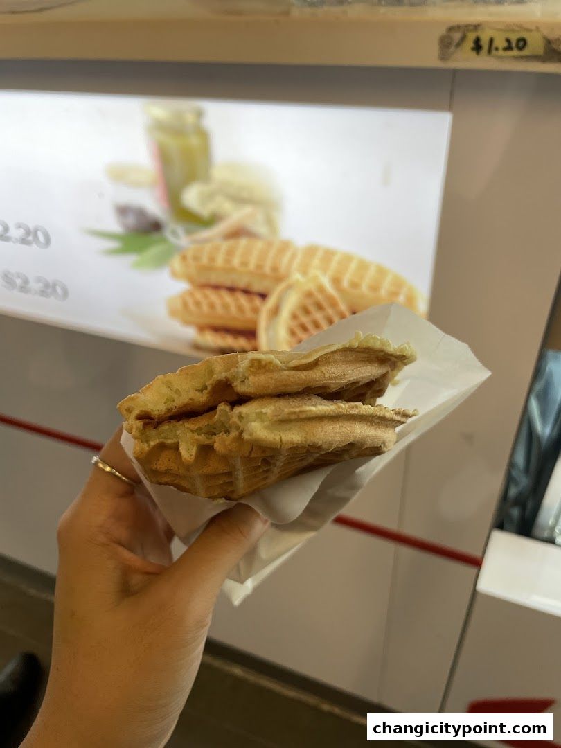 A hand holds a freshly made waffle sandwich from PrimaDéli.