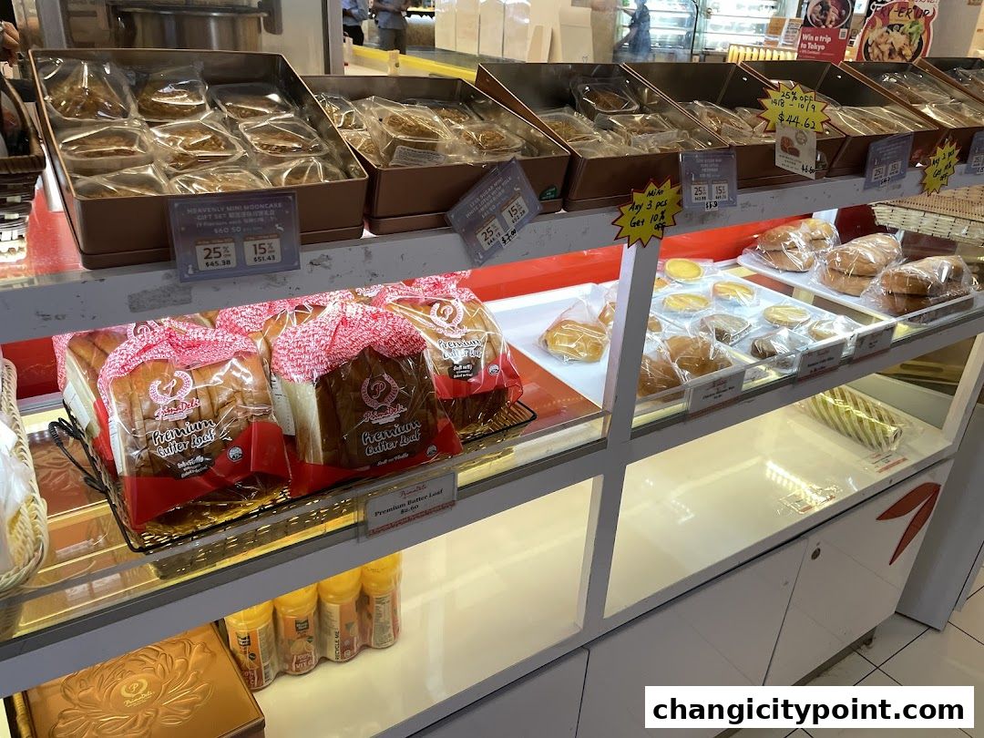 A display case filled with various baked goods, including mooncakes, bread loaves, and pastries.