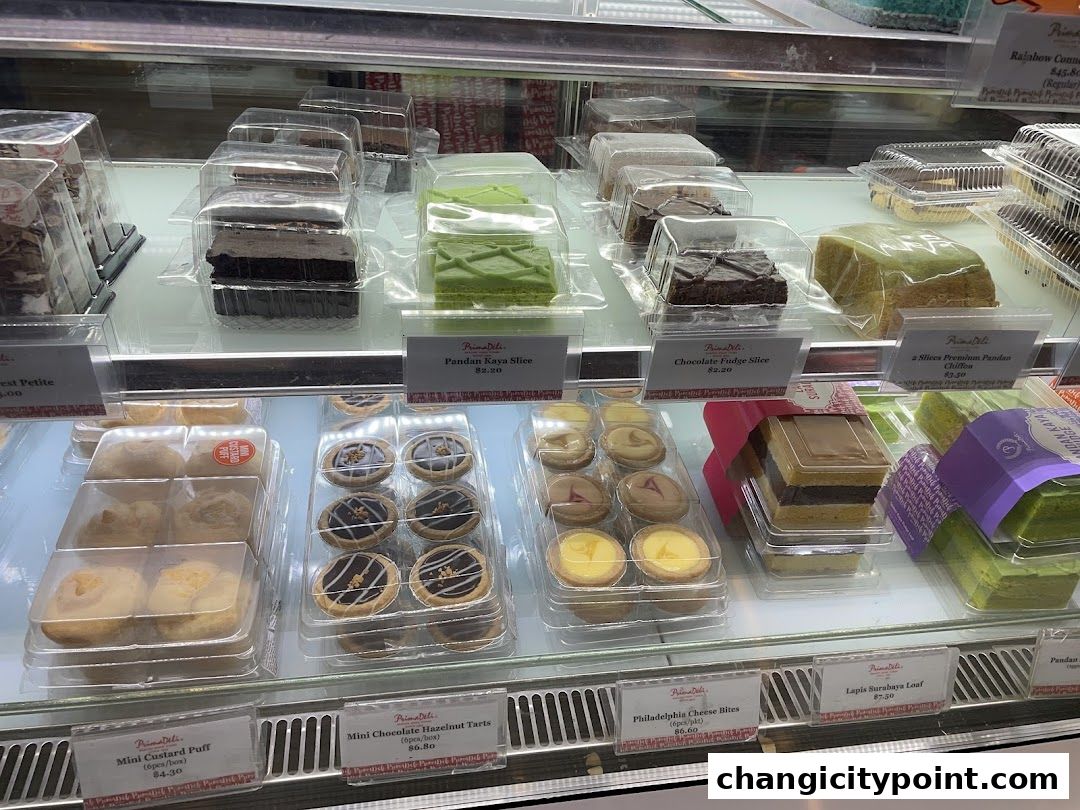A display case filled with various cakes, pastries, and desserts from PrimaDeli.