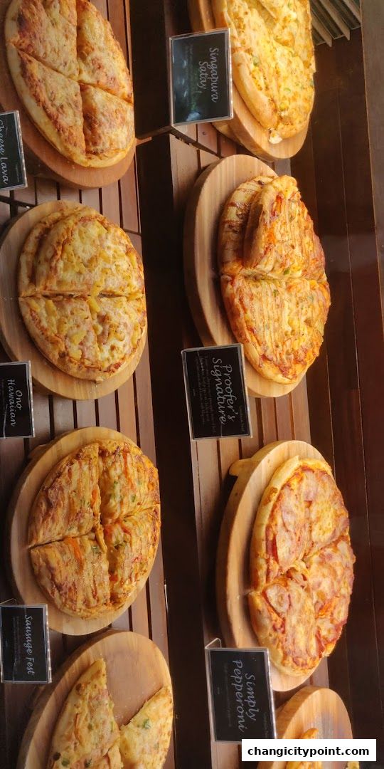 A display of various freshly baked pizzas and savory pastries at Proofer Boulangerie.