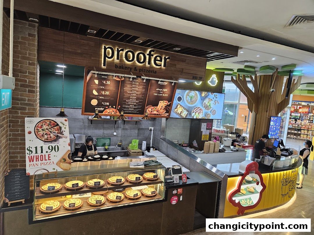 Interior view of Proofer Bakery & Pizzeria with a display of pizzas and a menu board.