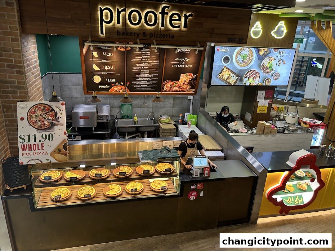 A bakery and pizzeria counter with pizzas displayed and a menu board above.