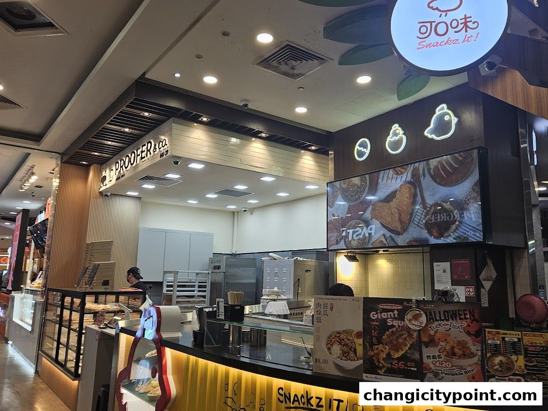 A bakery and snack shop counter with a display of food and promotional posters.