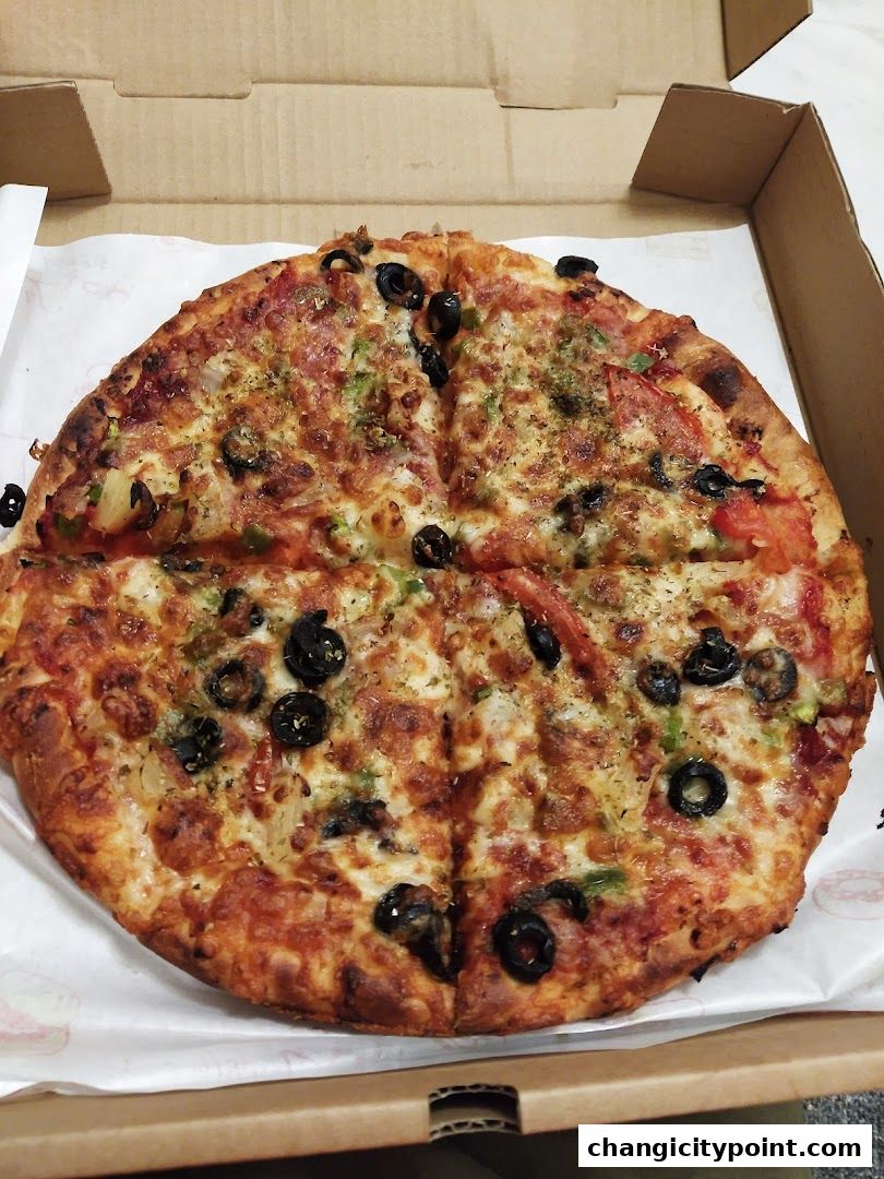 A delicious pizza with olives, peppers, and cheese in a cardboard box.