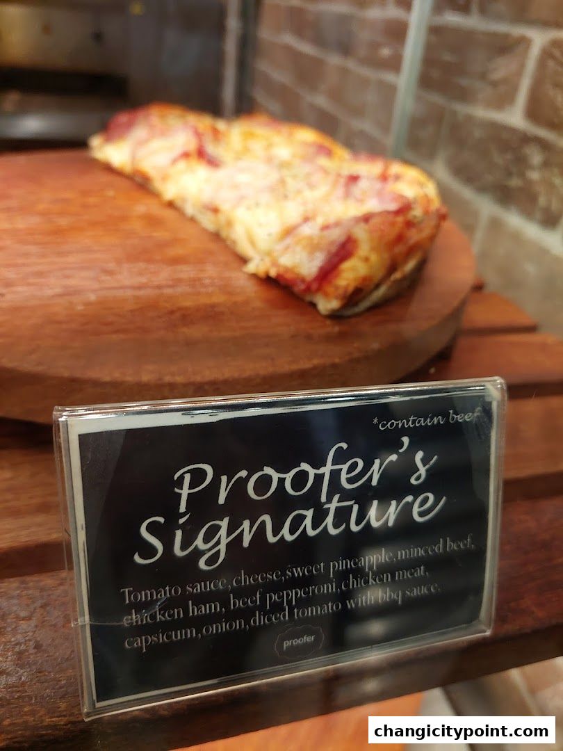 A slice of pizza labeled 'Proofer's Signature' with its ingredients listed.