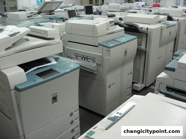 A large collection of printers and copiers are neatly arranged in a retail or storage space.
