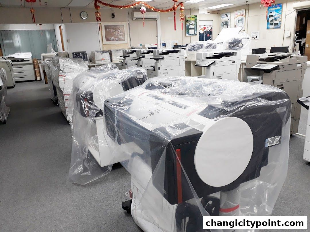 Interior view of a shop filled with printers and copiers, many covered in plastic.