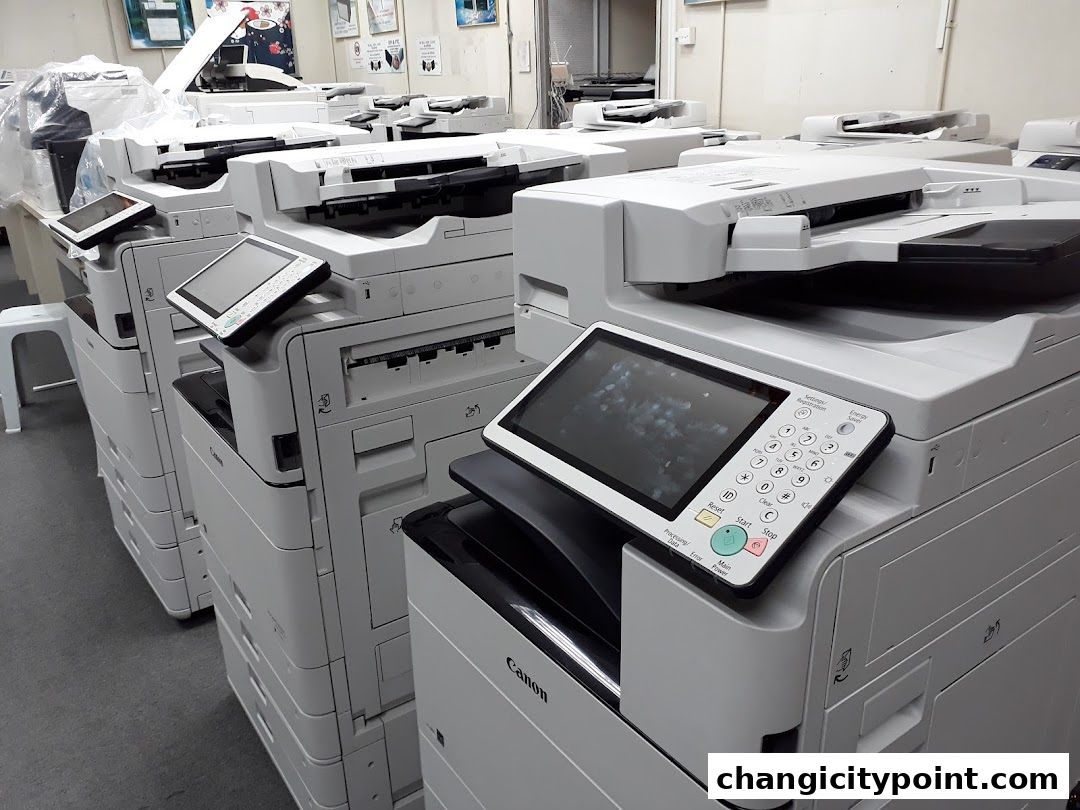 A row of modern Canon printers and copiers are displayed in a retail setting.