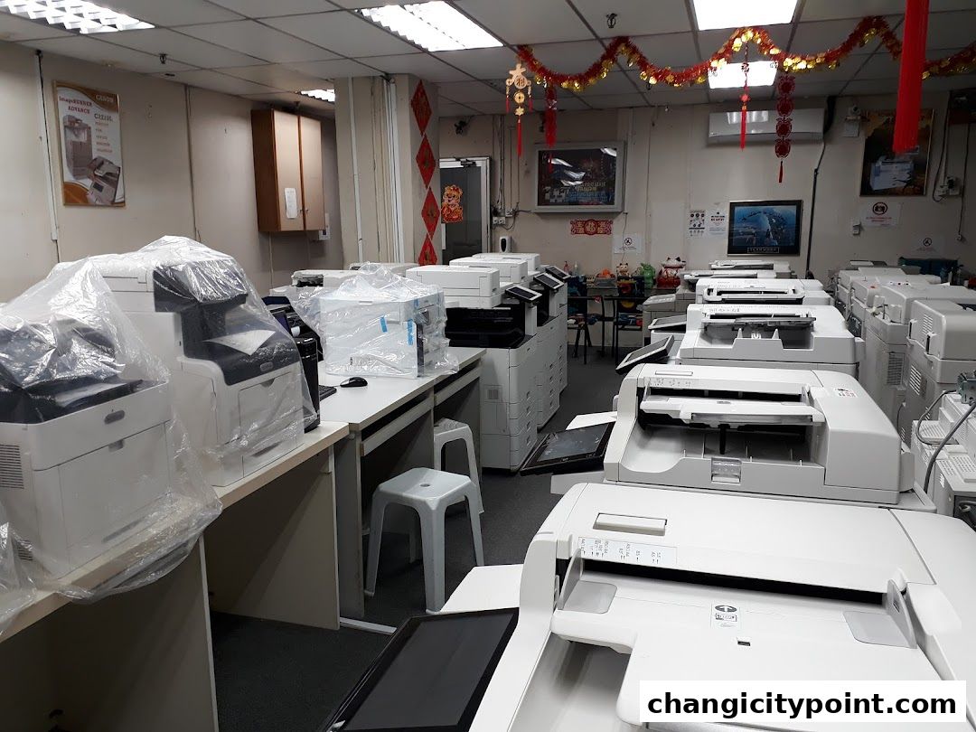 Interior view of a shop filled with printers and copiers, some covered in plastic.