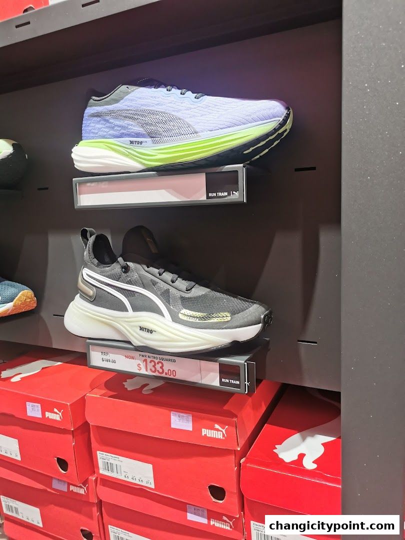 Puma running shoes displayed on shelves with price tags and boxes below.