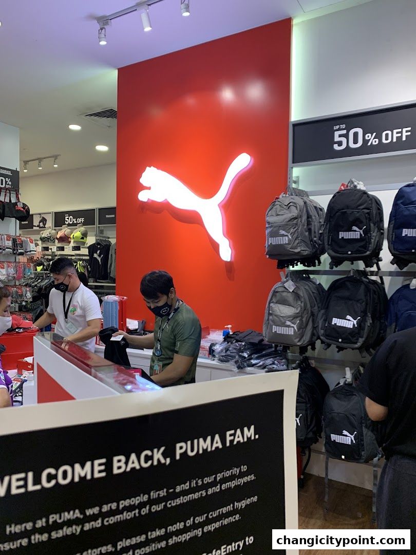 Puma store interior with staff, merchandise, and a large illuminated Puma logo.