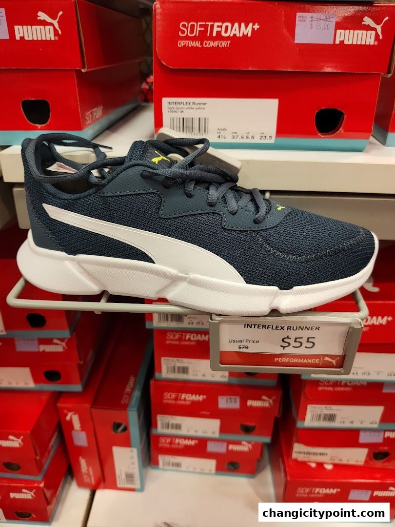 Puma Interflex Runner shoes displayed with their boxes and price tag.