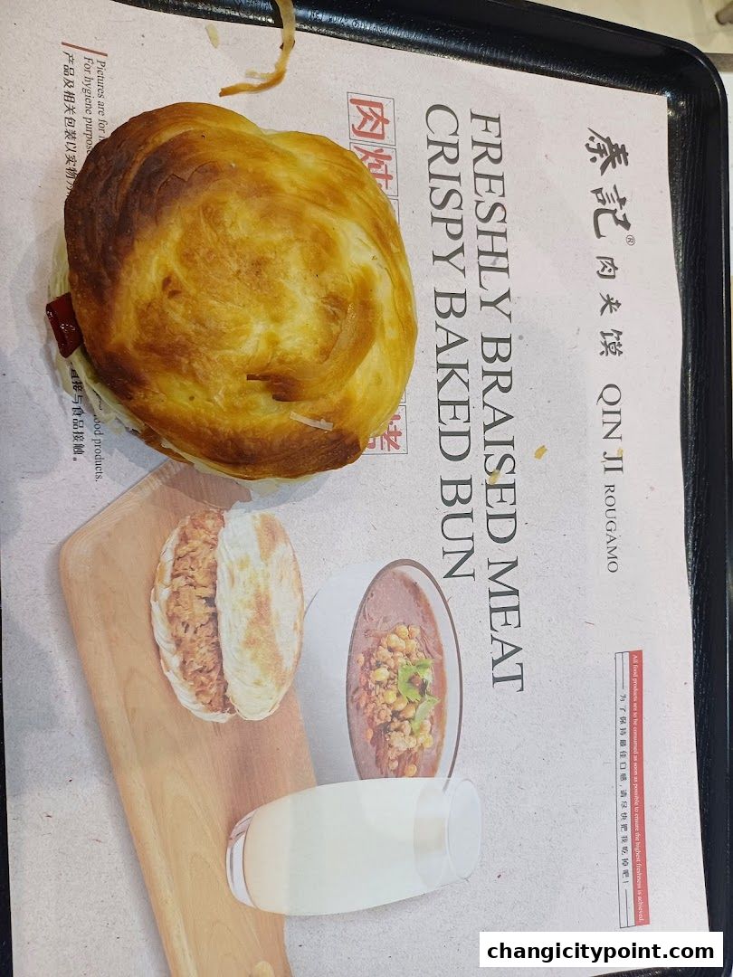 A close-up of a freshly baked bun filled with meat, with accompanying images of a roujiamo and a drink.