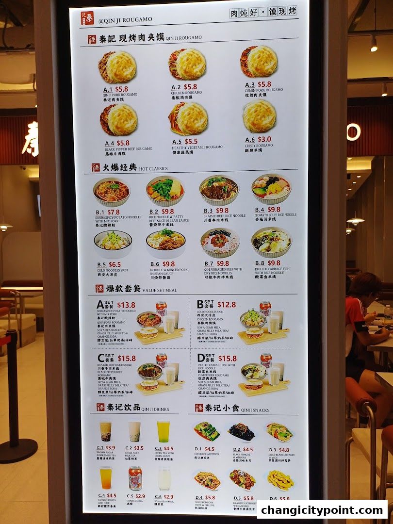 A digital menu board displaying various Rougamo, noodle dishes, set meals, drinks, and snacks from Qin Ji Rougamo.