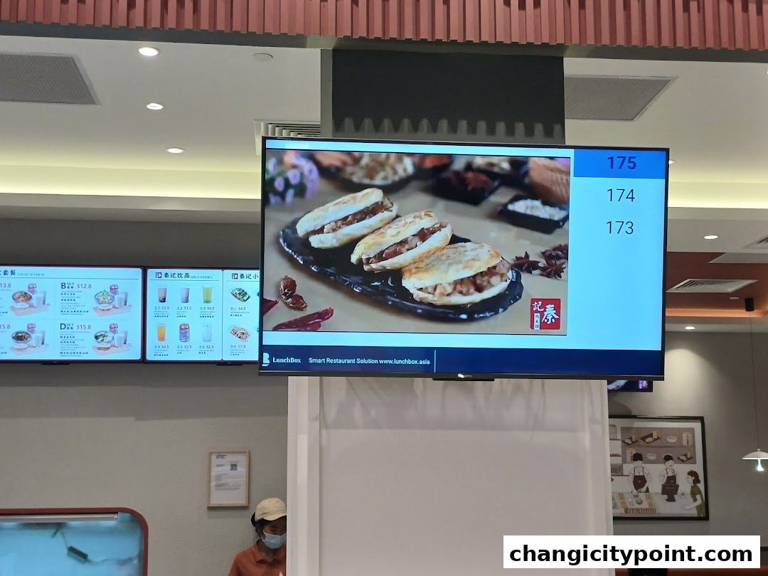 Digital menu boards display food items and order numbers at Qin Ji Rougamo.