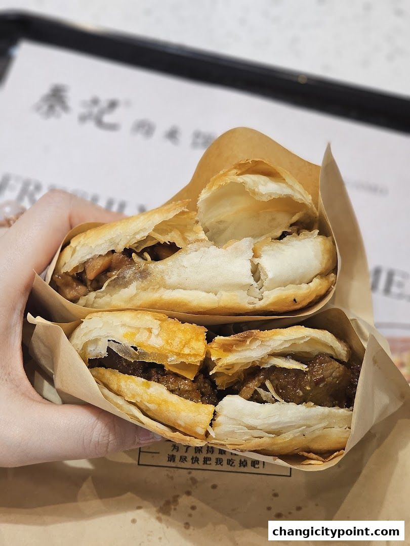 Two delicious Rougamo sandwiches held in hand, ready to be eaten.