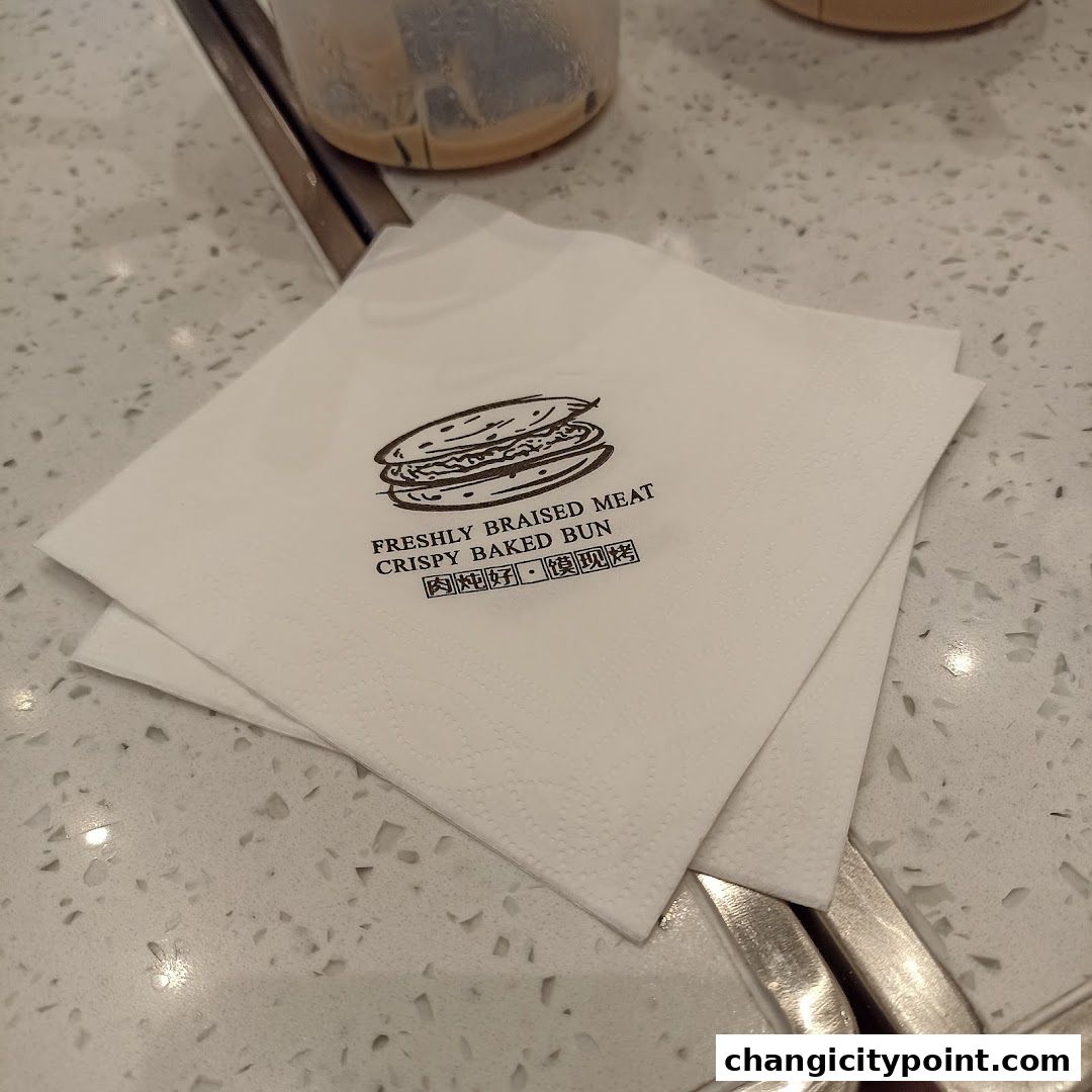 A napkin with the logo of Qin Ji Rougamo, featuring a burger and text.