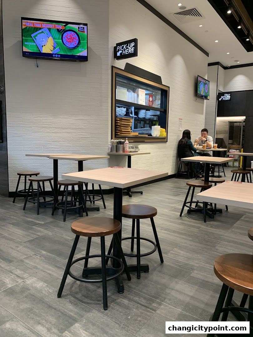 Interior of Real Thai restaurant with tables, stools, and a pick-up counter.