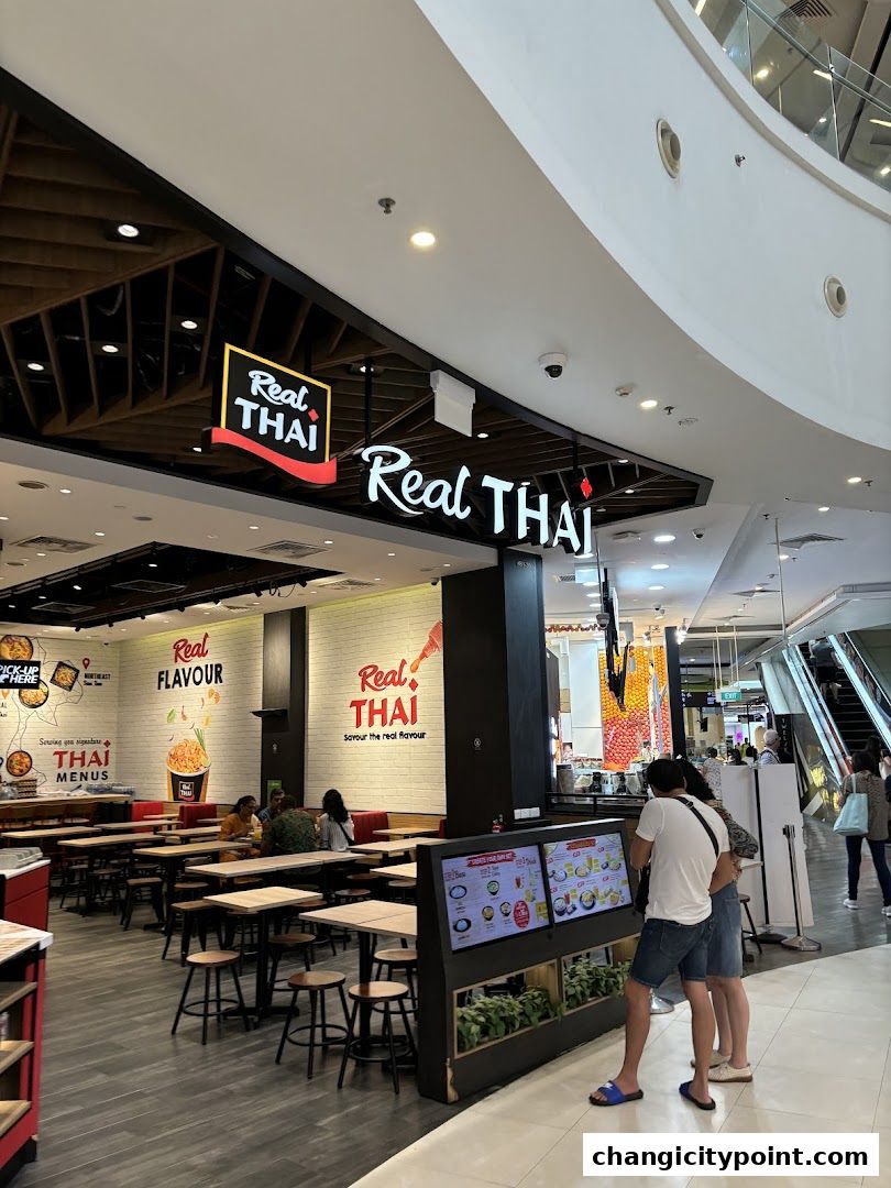 The exterior of a Real Thai restaurant with seating and a digital menu display.
