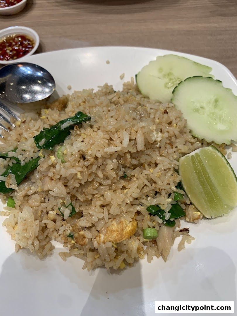 A plate of delicious Thai fried rice with cucumber slices and lime wedge.