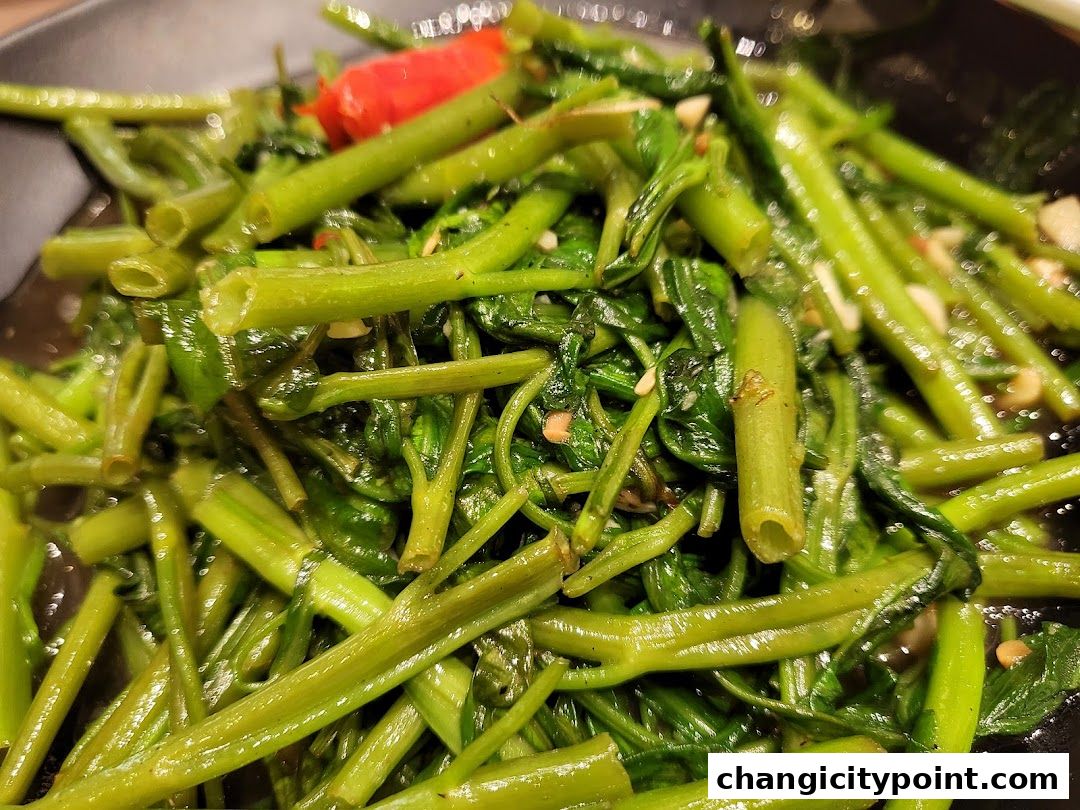 A close-up shot of stir-fried water spinach with chili and garlic.
