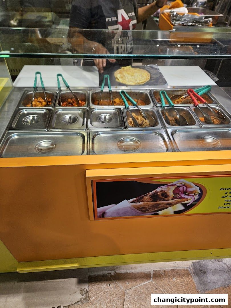 A food counter with various fillings and a flatbread, ready to be made into wraps.