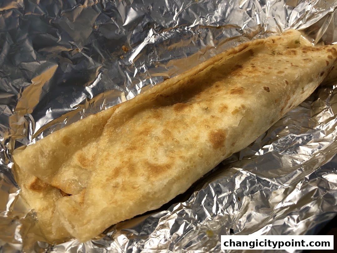 A delicious wrap, likely a roll, is presented on a bed of crumpled aluminum foil.