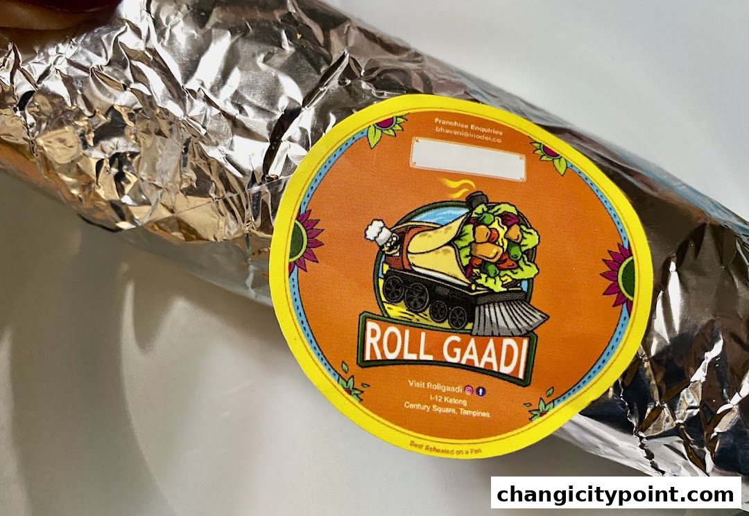 A foil-wrapped food item with a colorful circular sticker from Roll Gaadi.