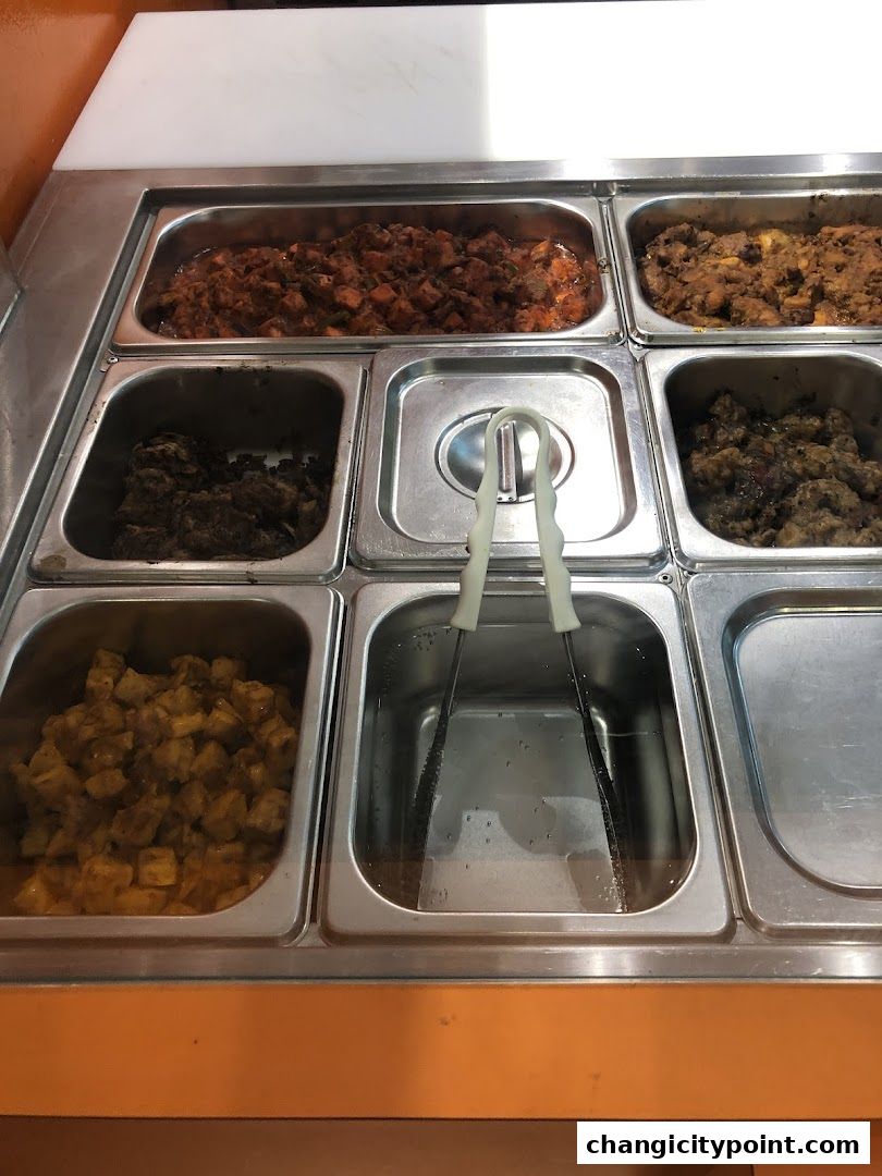 A close-up view of a food display with multiple stainless steel containers filled with various dishes.