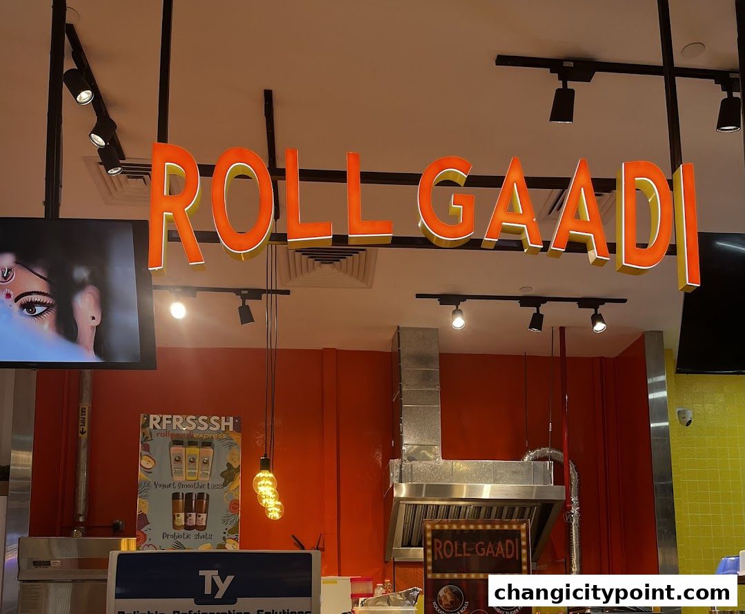 The illuminated sign for 'RollGaadi' is prominently displayed above a food counter with kitchen equipment.