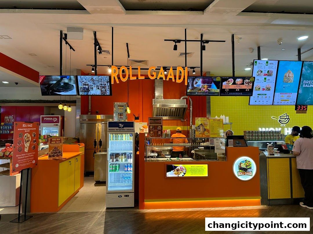 The RollGaadi shop front with bright orange counters, digital menus, and staff serving customers.