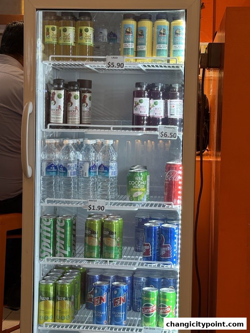 A refrigerator stocked with various beverages including Lassi, juices, water, and sodas.