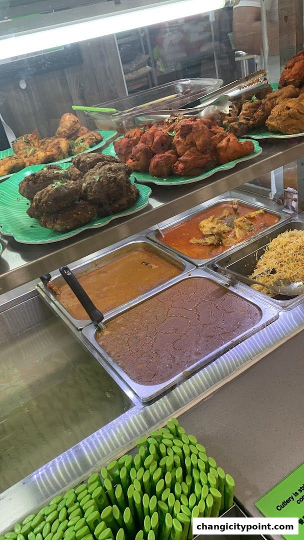 A display of various Indian dishes, including curries, fried chicken, and rice, ready for serving.