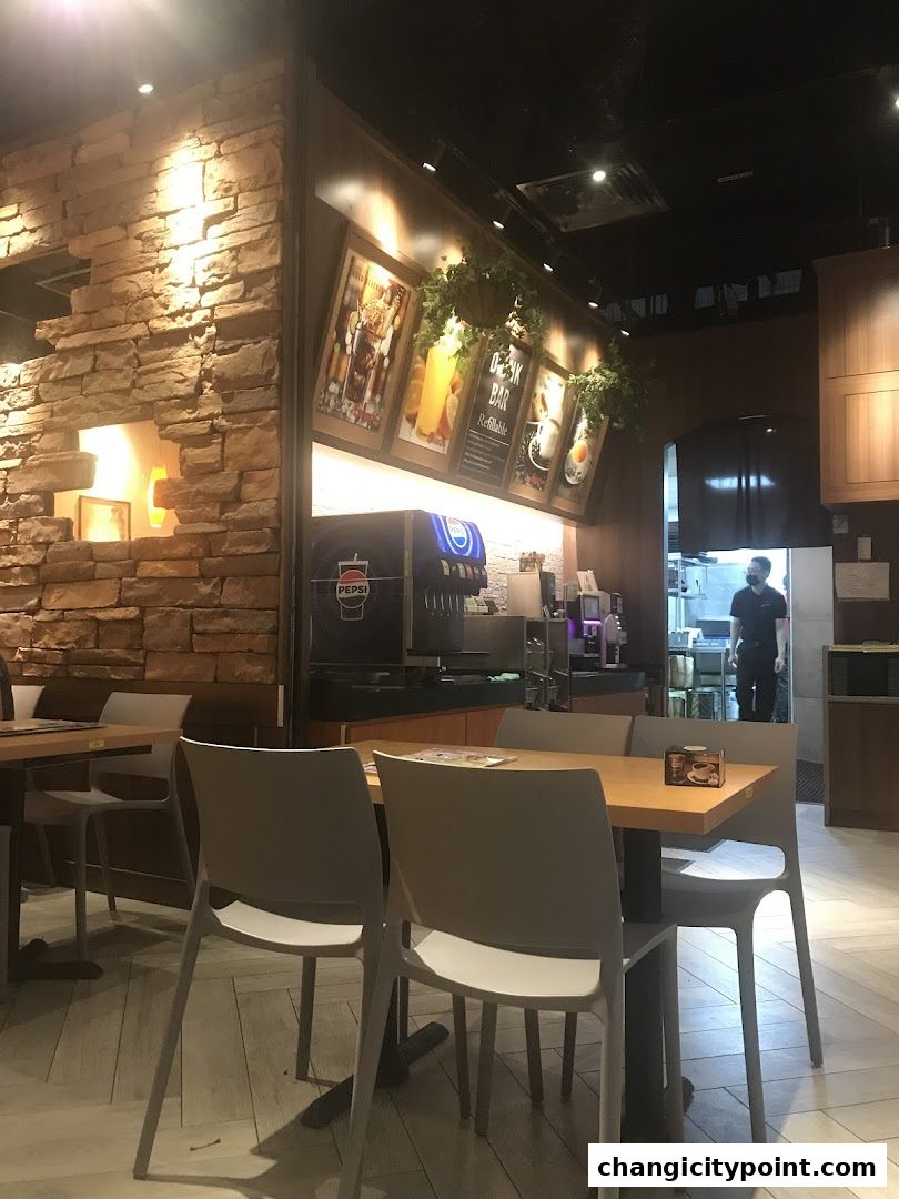 Interior of a Saizeriya restaurant with tables, chairs, and a drink bar.