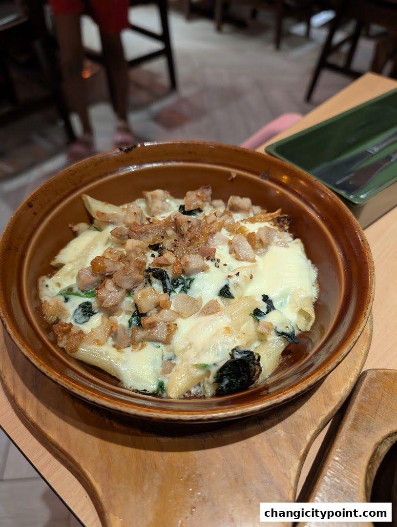 A close-up of a baked pasta dish with cheese, spinach, and meat in a brown bowl.