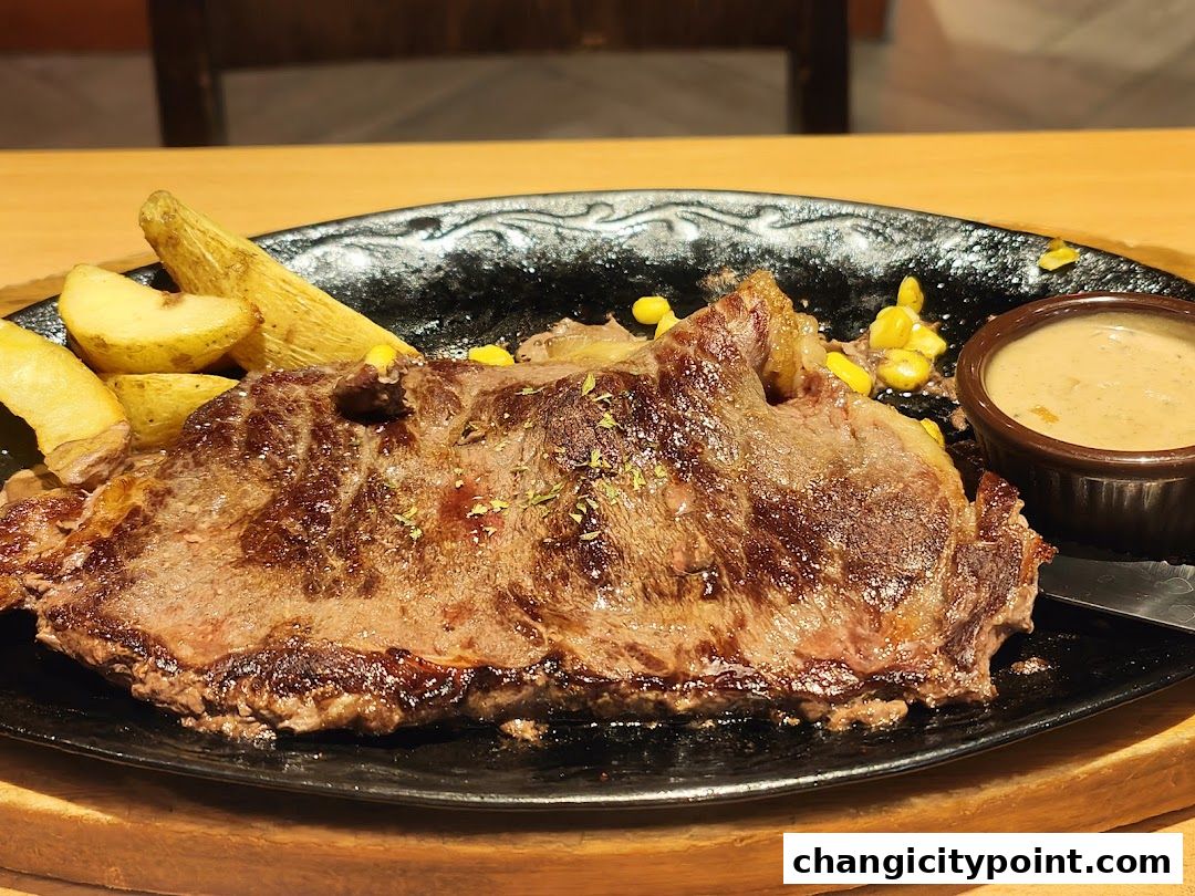 A juicy steak served with potato wedges, corn, and a side of sauce.