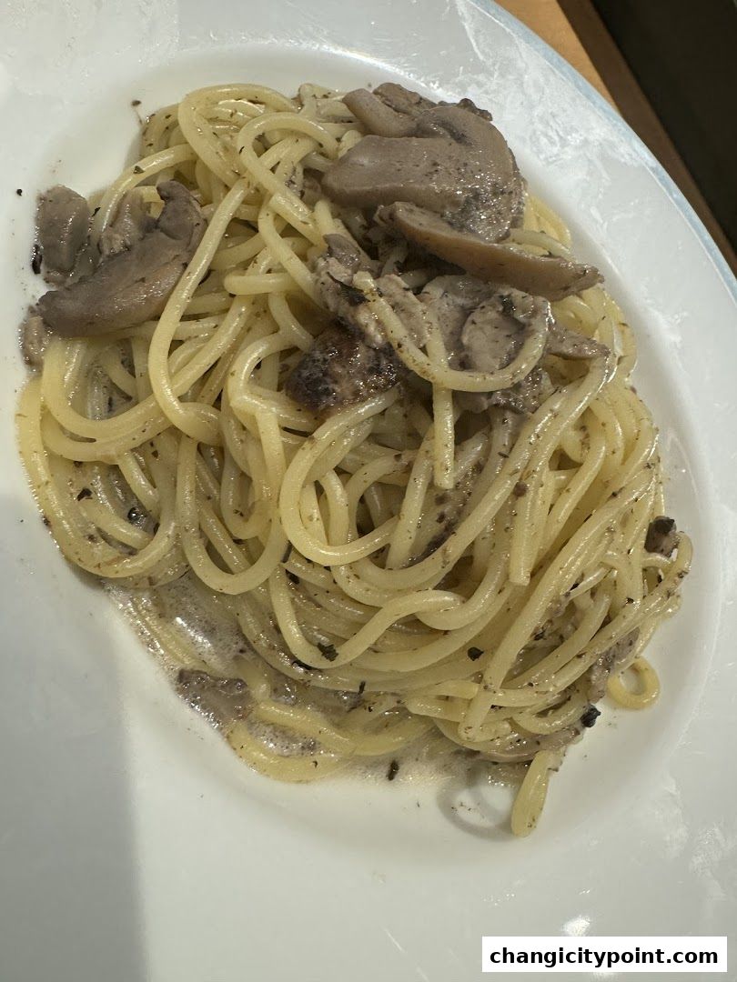 A close-up shot of a plate of spaghetti with mushrooms and a creamy sauce.