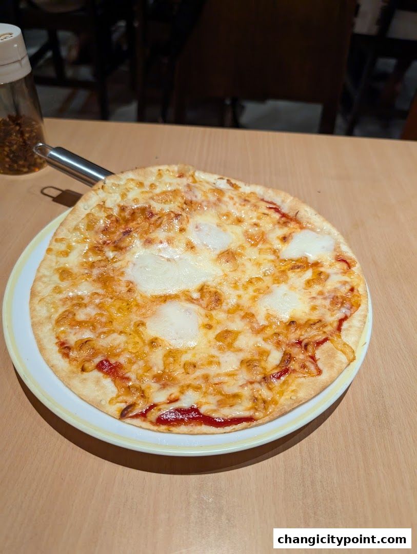 A delicious cheese pizza served on a plate with a shaker of red pepper flakes.
