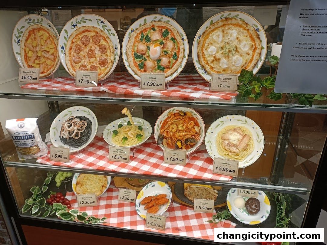 A display case showcasing realistic food models of pizzas, pastas, and other dishes with prices.