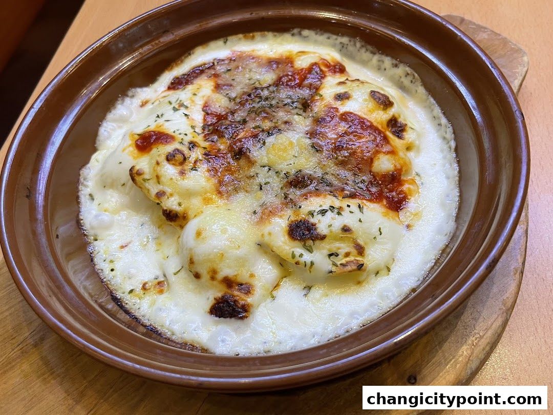 A close-up of a baked dish with melted cheese and herbs in a brown ceramic bowl.